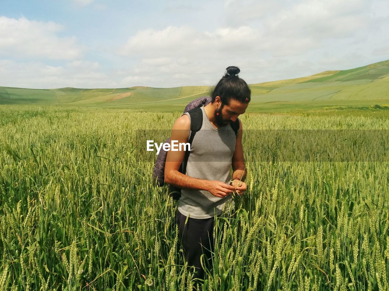 Man standing amidst crops on agricultural field against sky