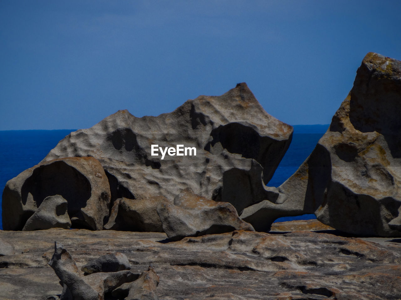 ROCKS IN SEA AGAINST BLUE SKY