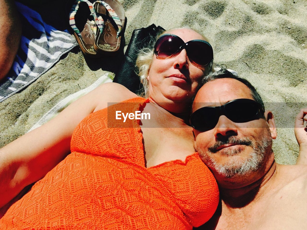 High angle view of mature couple resting at beach on sunny day