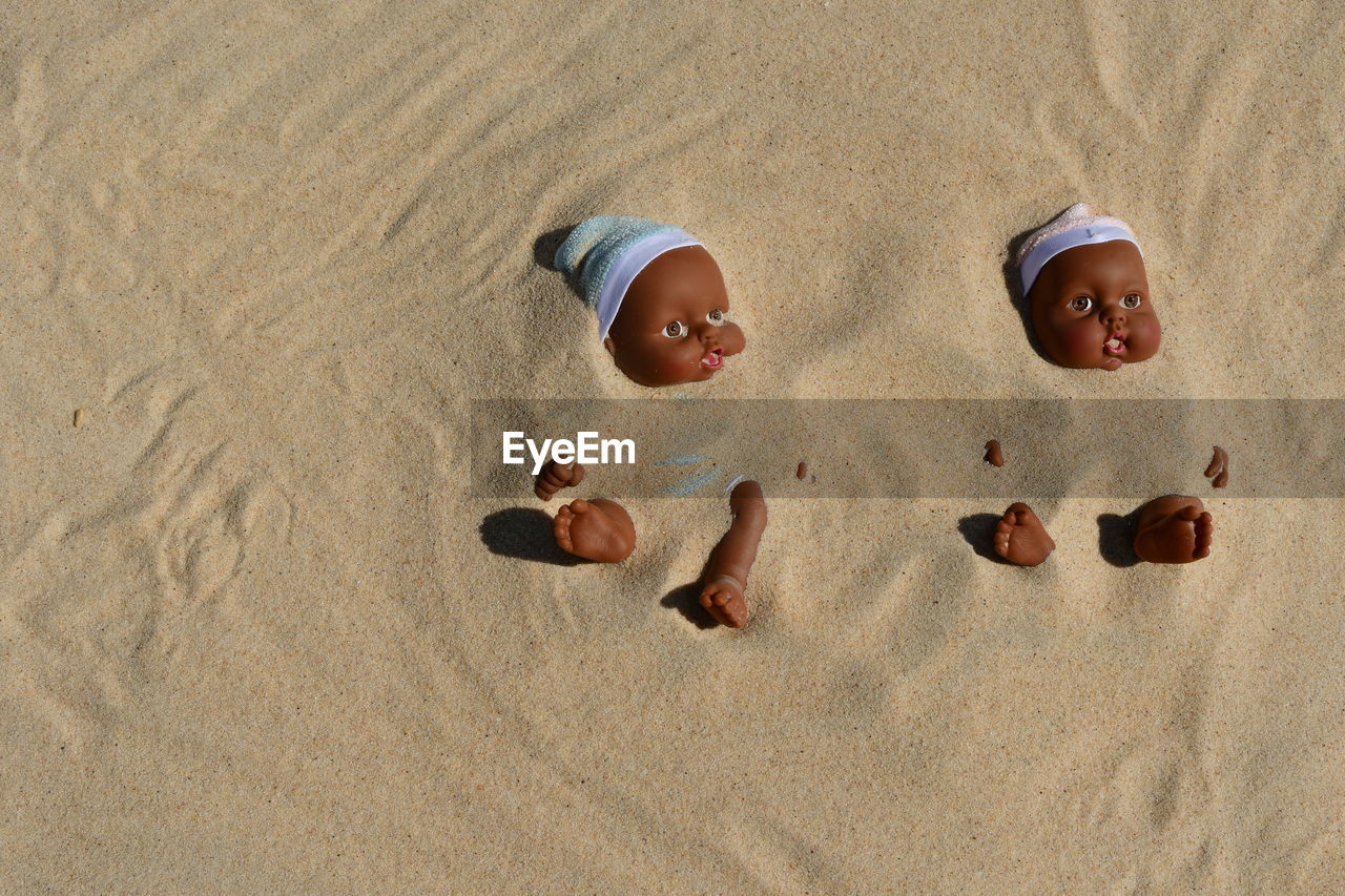 High angle view of dolls buried in sand at beach