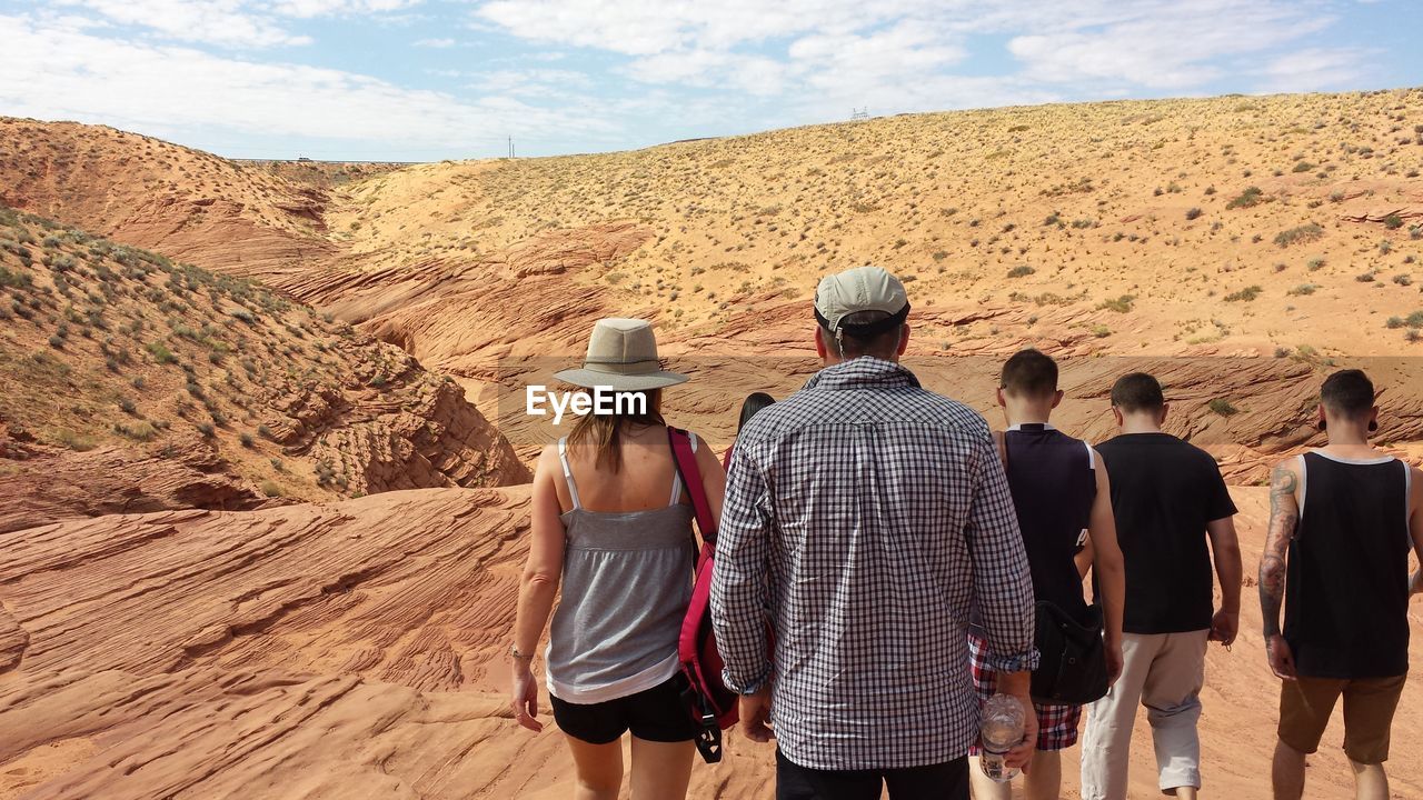 Rear view of people walking on desert against sky