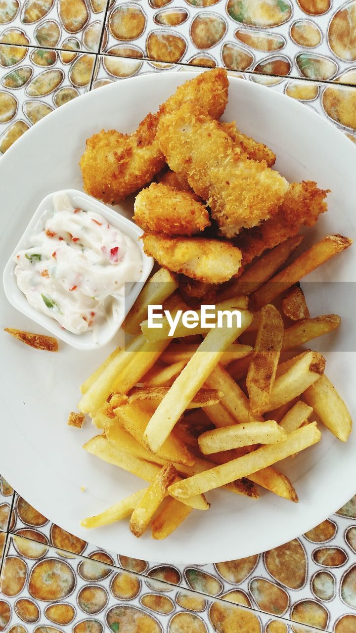 French fries and fish with dip in plate on tiled floor