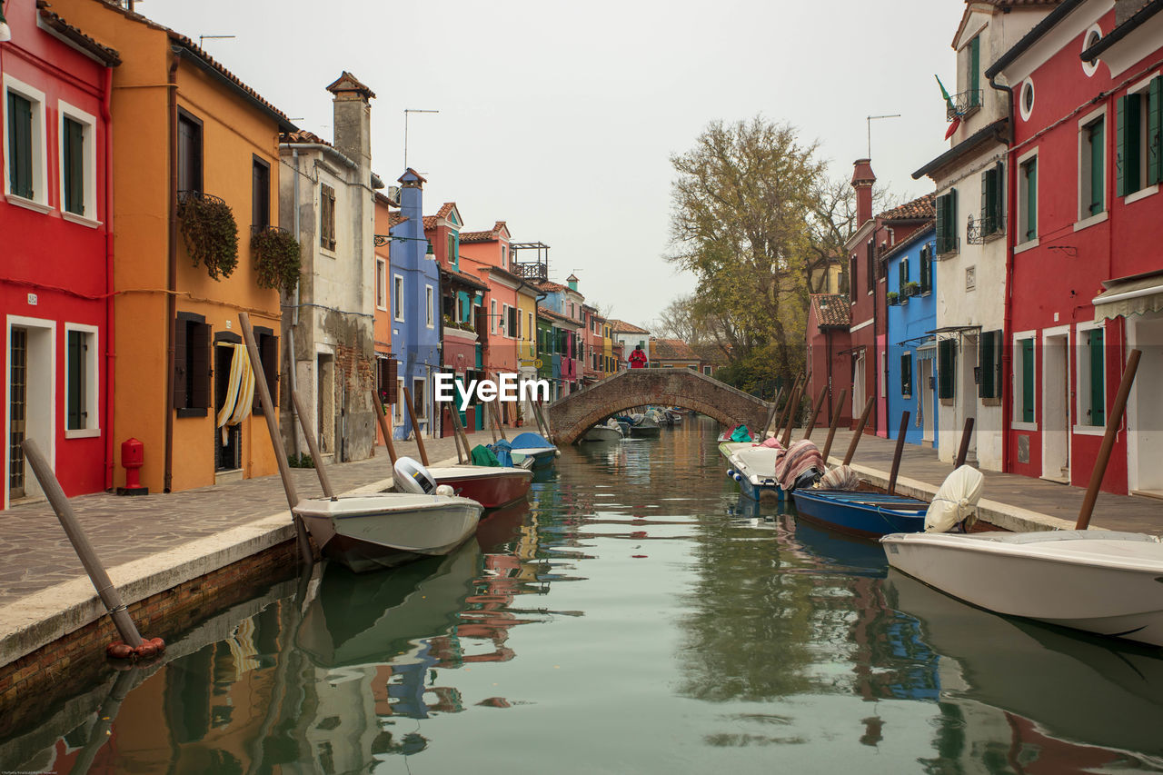 Boats moored in canal amidst buildings in city