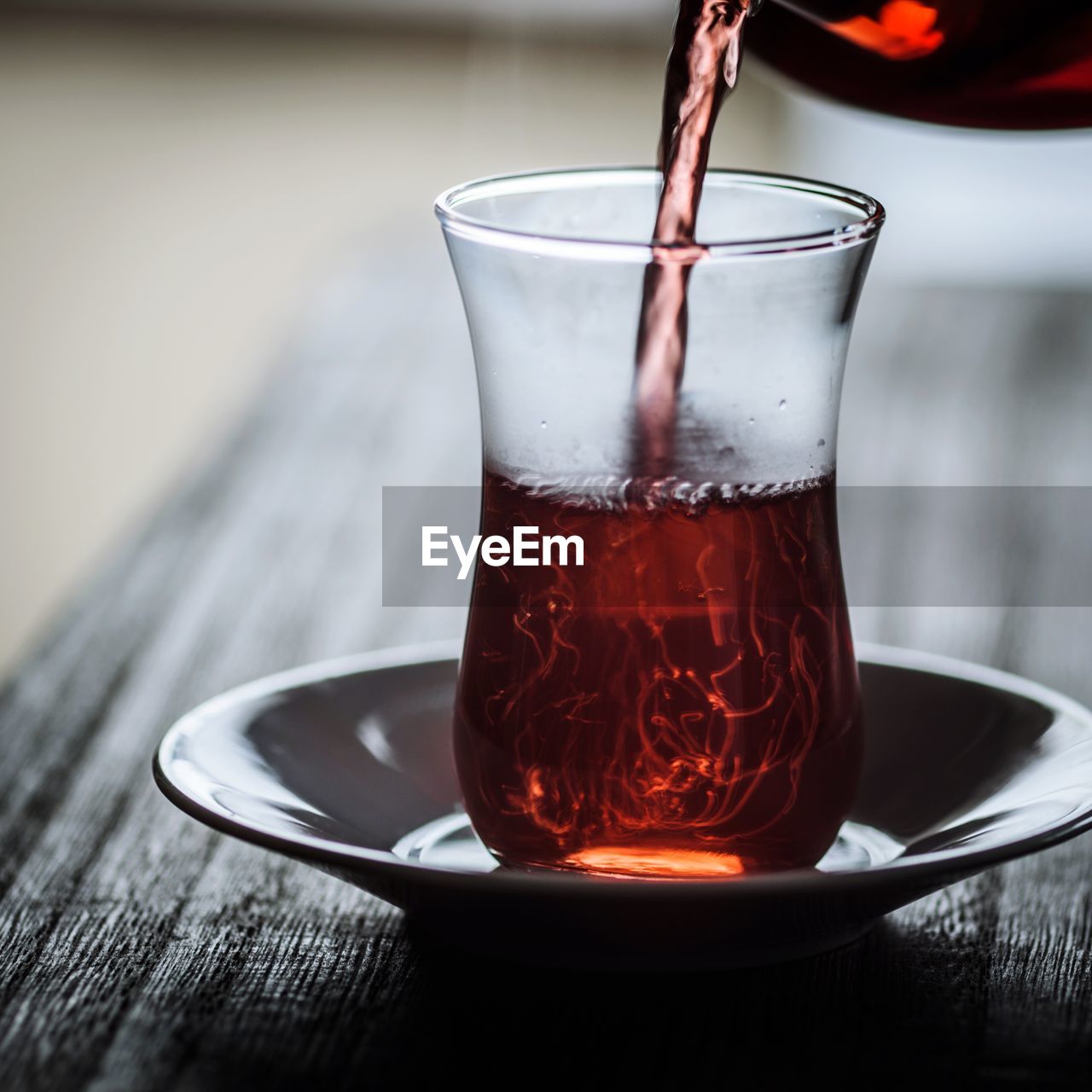Tea being poured in glass on wooden table