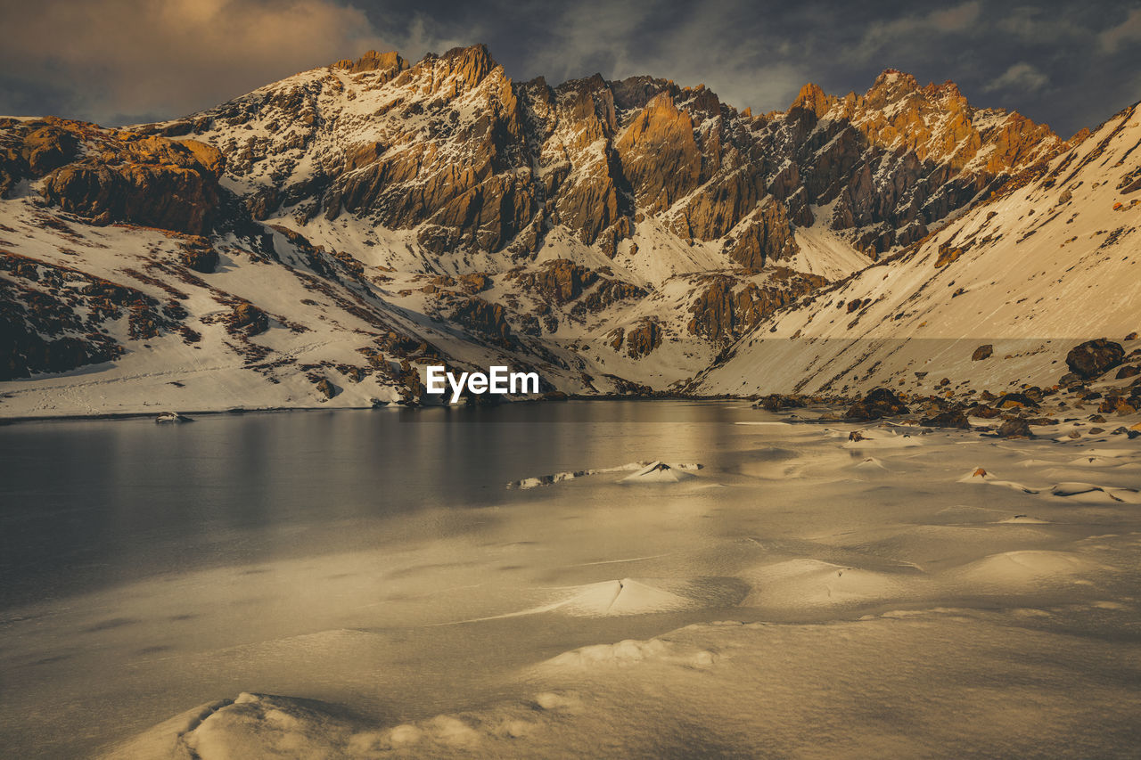 Scenic view of lake by snowcapped mountains against sky