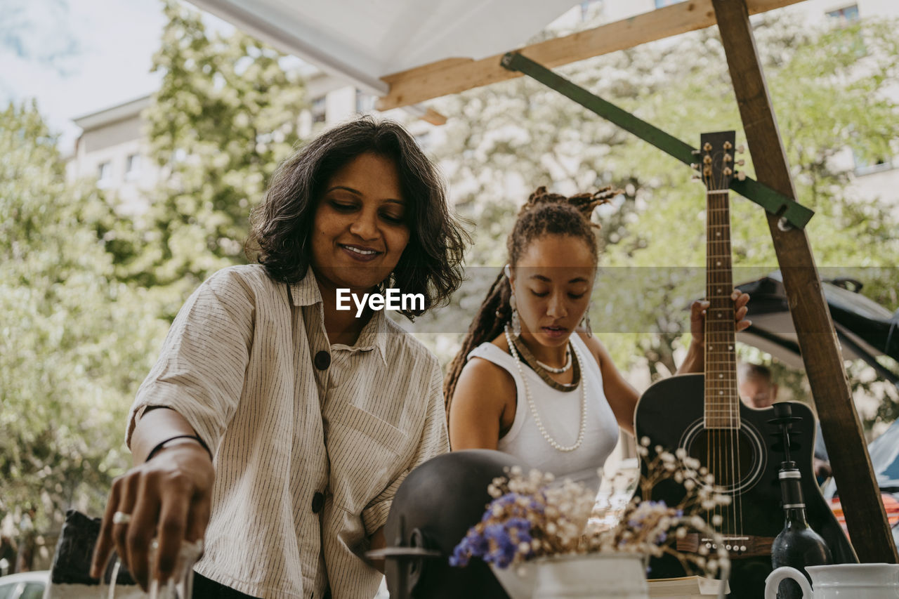 Female partners arranging products at flea market