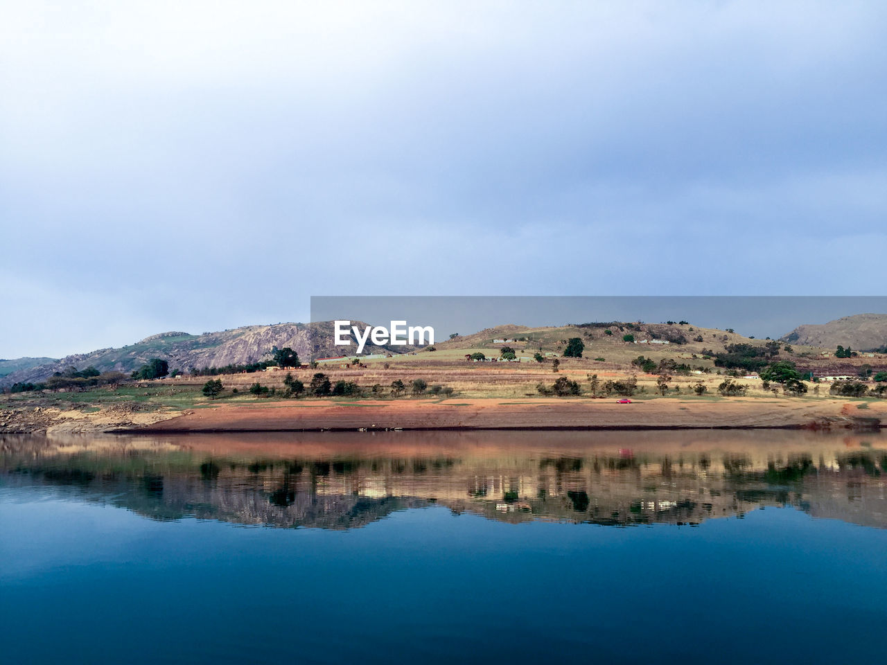 REFLECTION OF MOUNTAINS IN LAKE AGAINST SKY