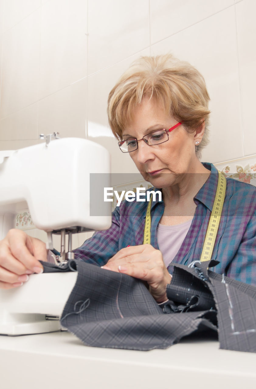 Senior woman using sewing machine at workshop