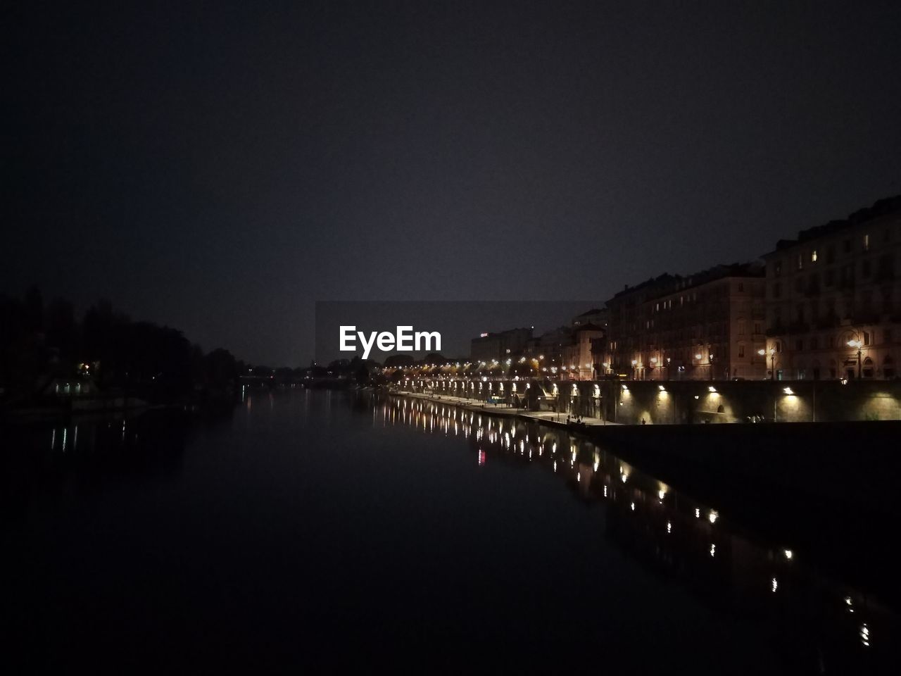 RIVER BY ILLUMINATED CITY AGAINST CLEAR SKY AT NIGHT