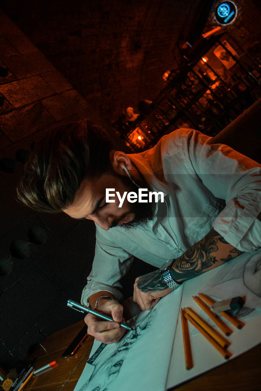 HIGH ANGLE VIEW OF WOMAN WORKING AT ILLUMINATED SHOP