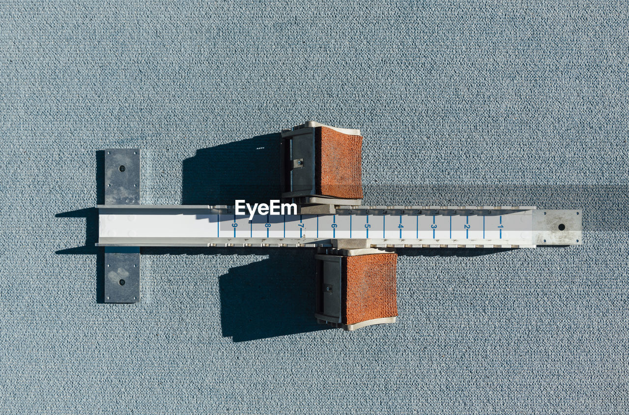 From above top view starting blocks placed on blue racetrack during track and field training on sunny day on stadium