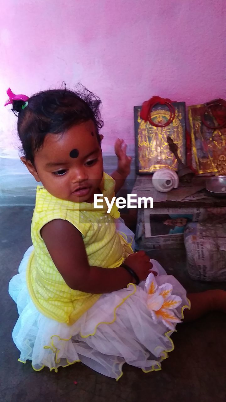 PORTRAIT OF CUTE BABY GIRL SITTING AT HOME