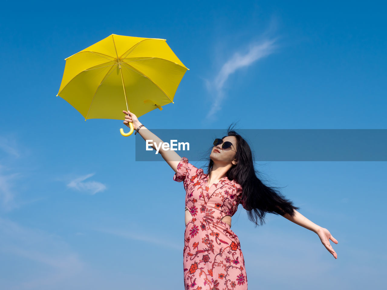 Low angle view of woman holding umbrella against sky