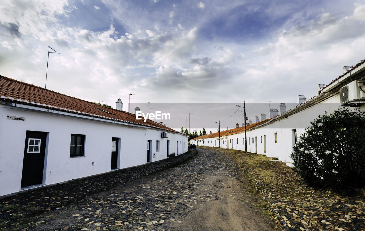 Road amidst buildings against sky