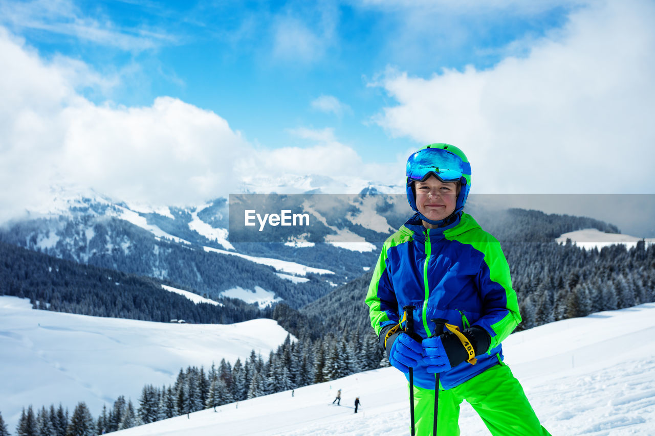 portrait of boy standing on snow covered mountain against sky