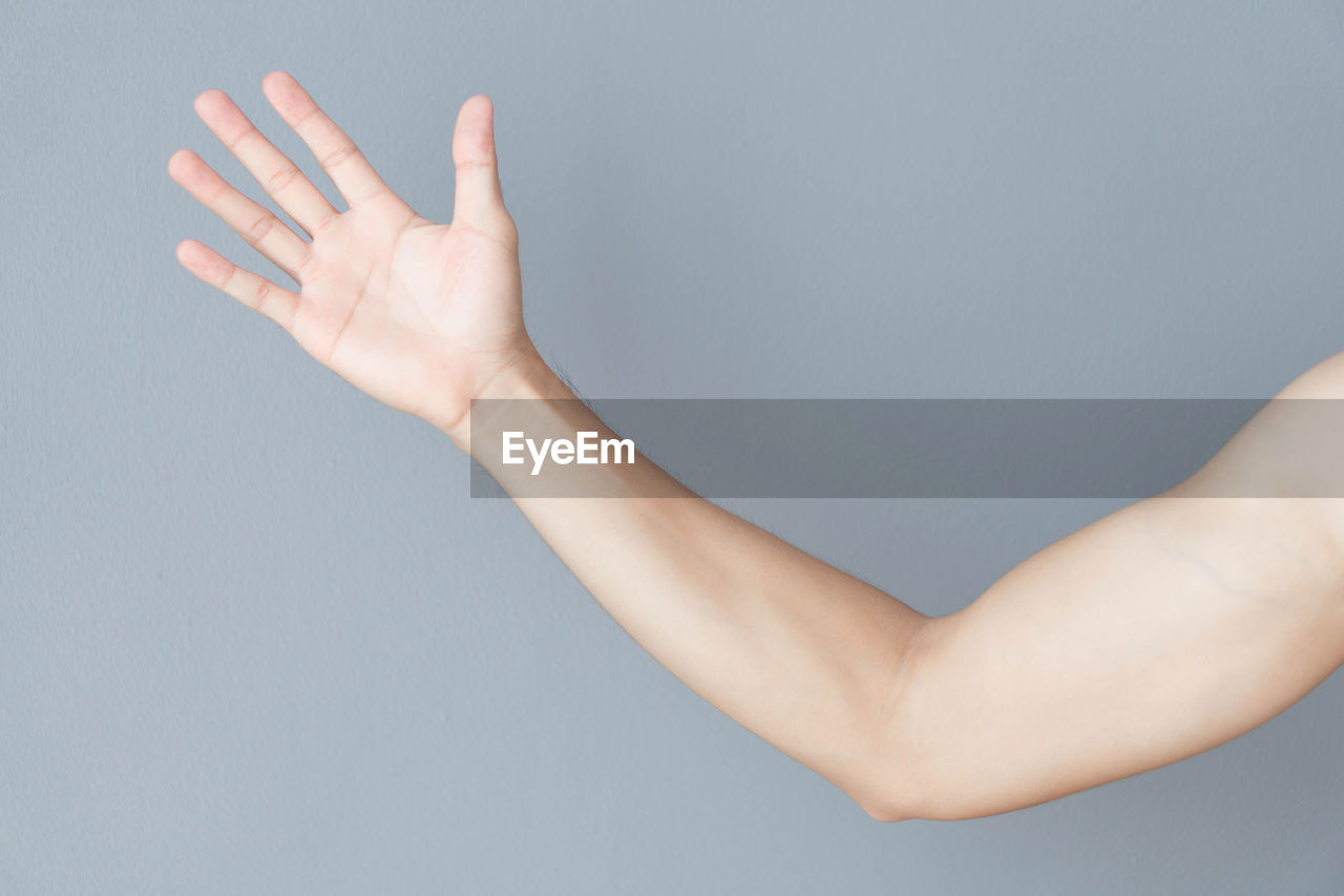 Cropped hand of man gesturing over gray background