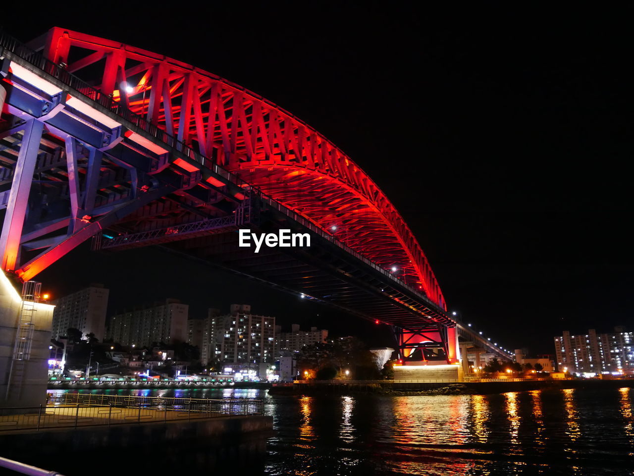 LOW ANGLE VIEW OF ILLUMINATED BRIDGE OVER RIVER AGAINST SKY