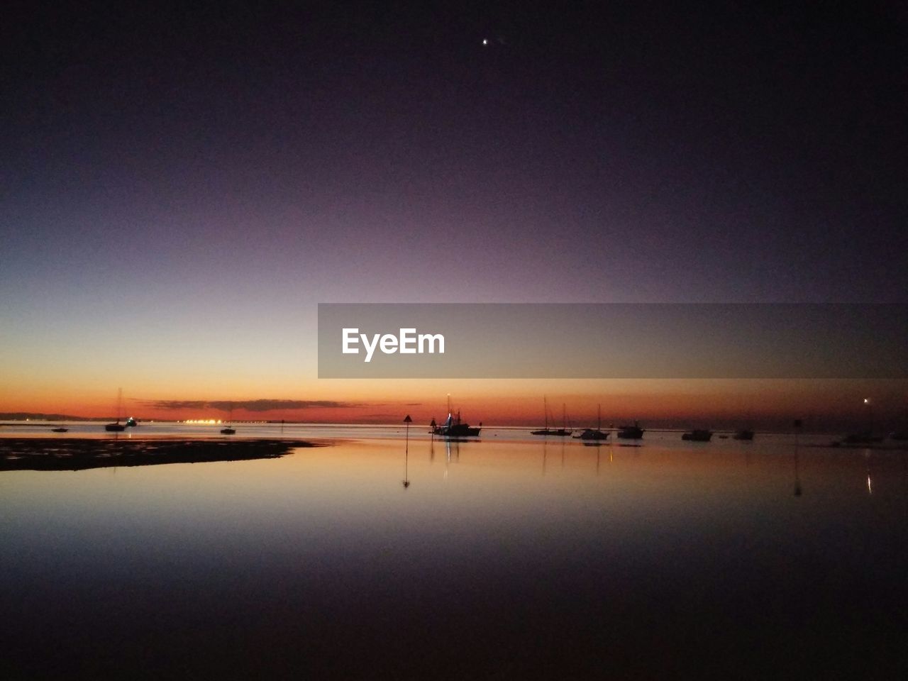 Silhouette boats in calm sea against clear sky