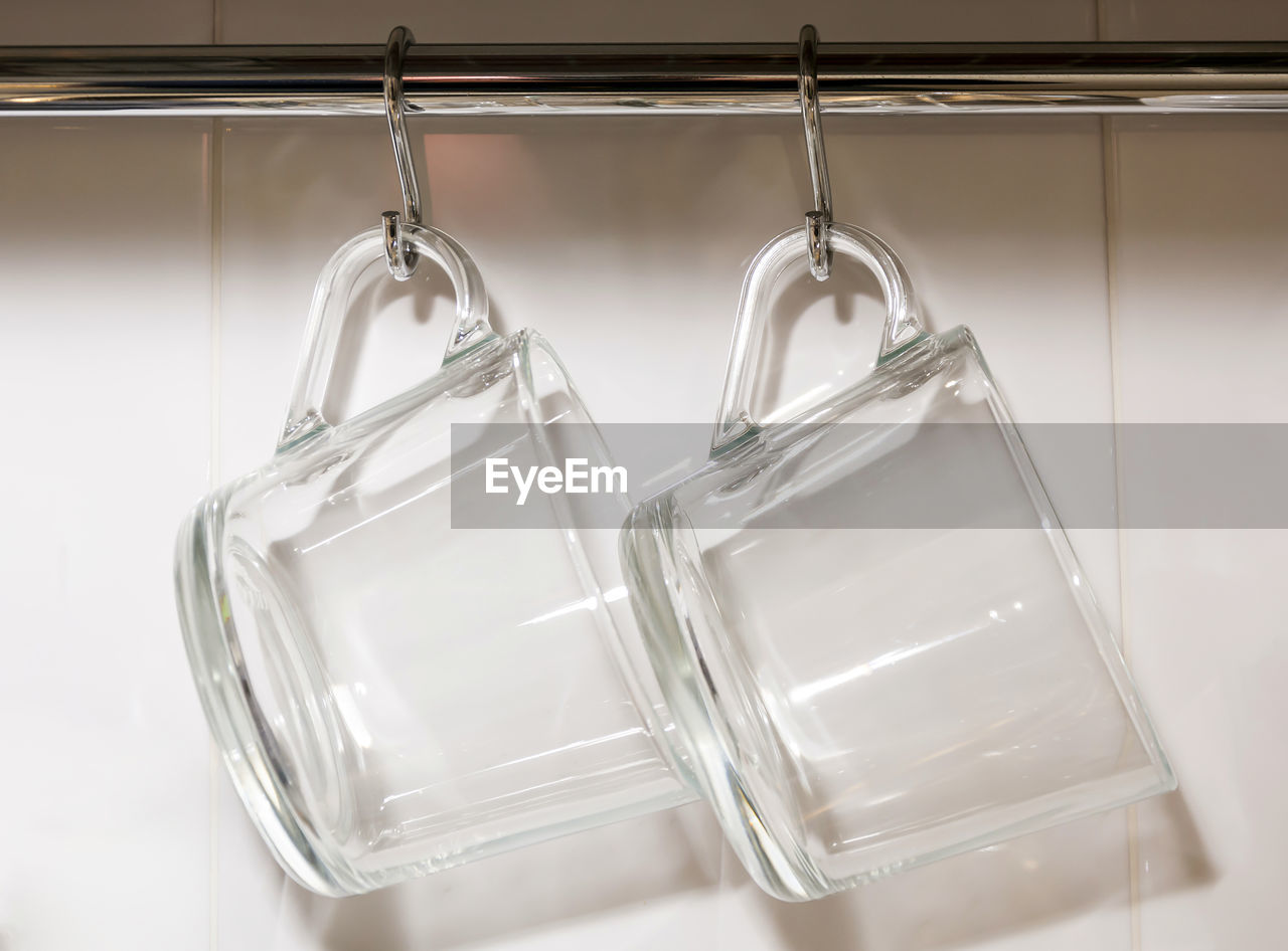 Close-up of cups hanging against wall in kitchen at home