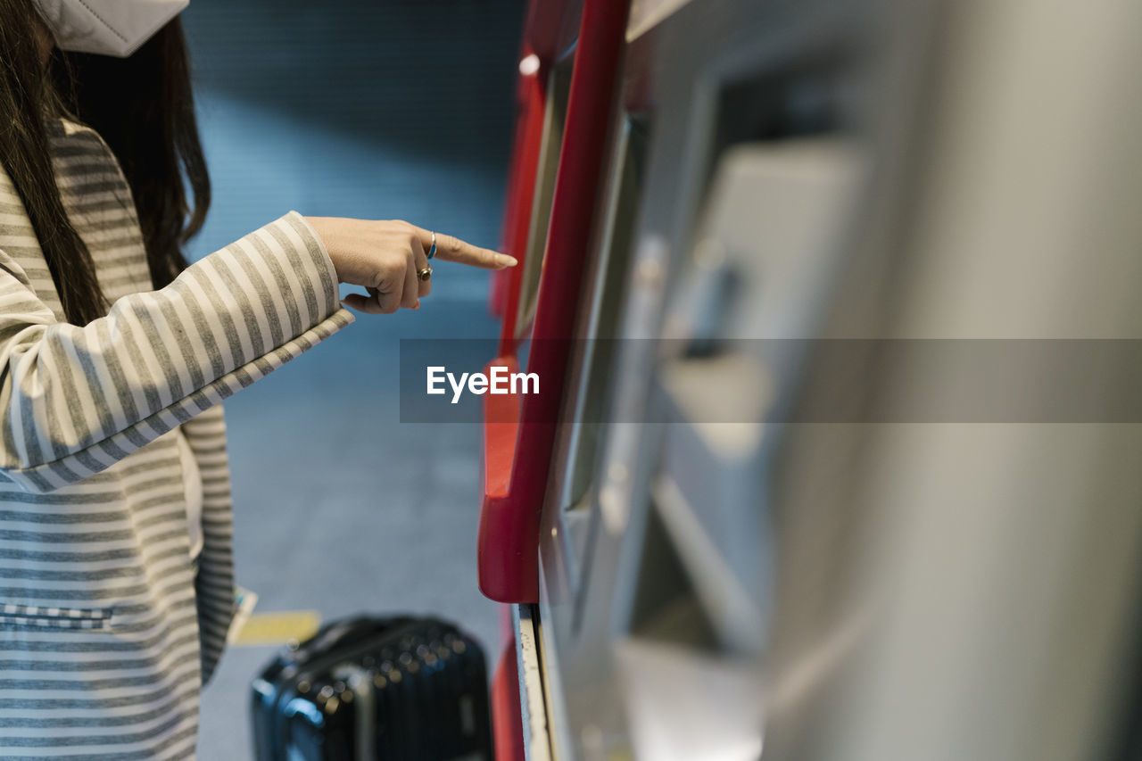 Female passenger buying ticket from kiosk during covid-19