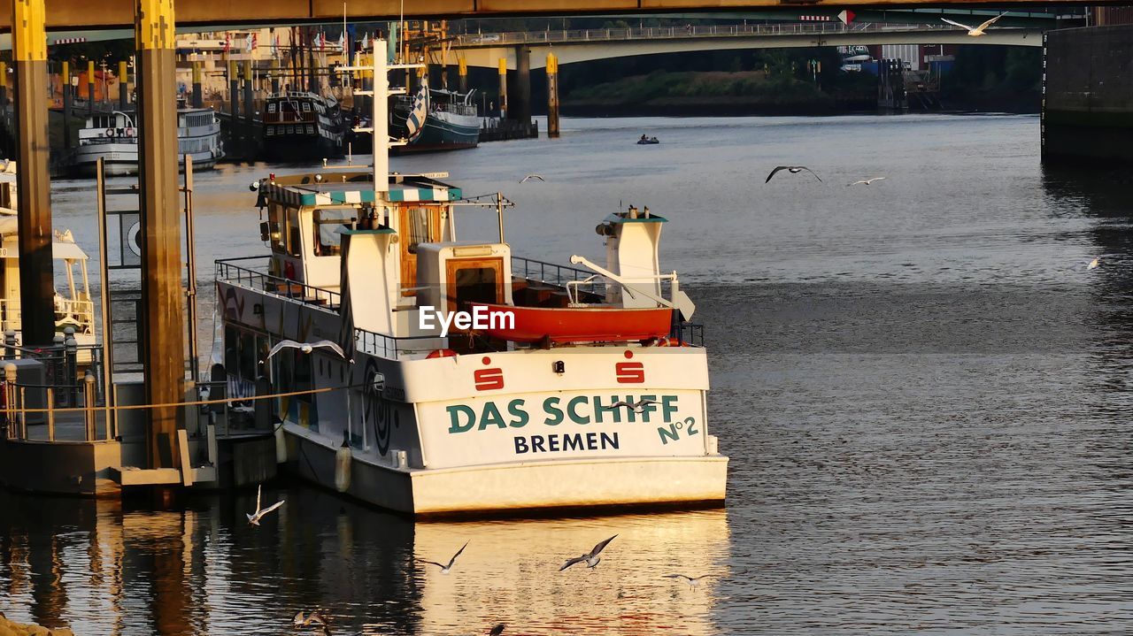 BOATS ON PIER BY RIVER