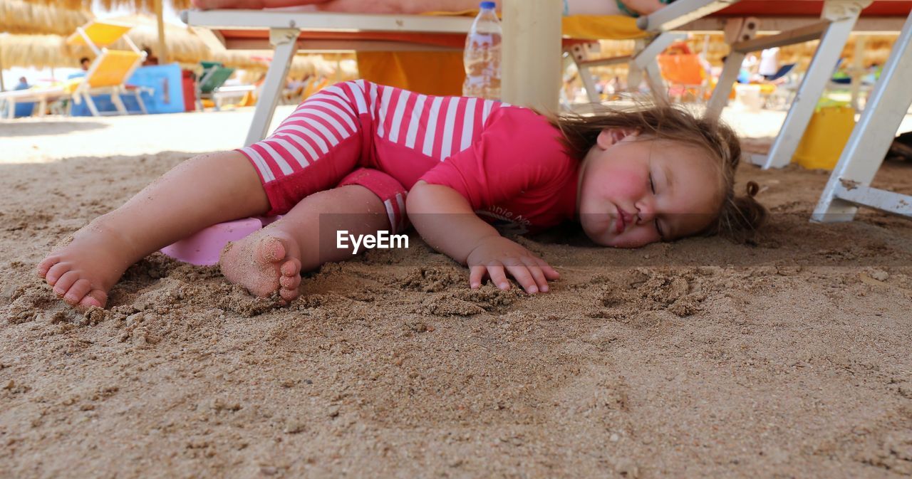childhood, child, sand, lying down, one person, beach, person, full length, baby, relaxation, innocence, toddler, eyes closed, clothing, land, day, barefoot, playground, lying on front, leisure activity, nature, fun, human leg, cute, emotion, female, lifestyles, outdoors, crawling, enjoyment, summer, men, human face