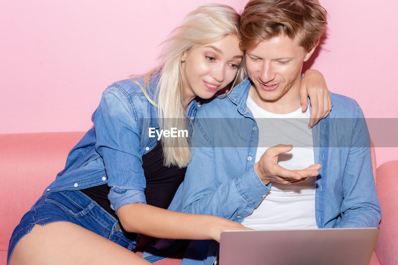 Couple using laptop while sitting on sofa at home