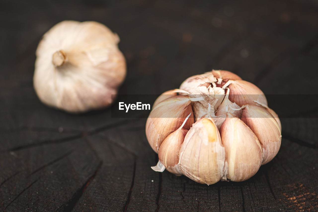 Garlic bulbs and cloves on a black wooden rustic board background, close up