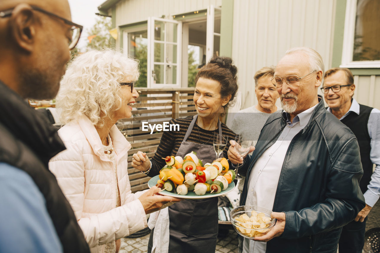 Smiling senior women and men enjoying garden party