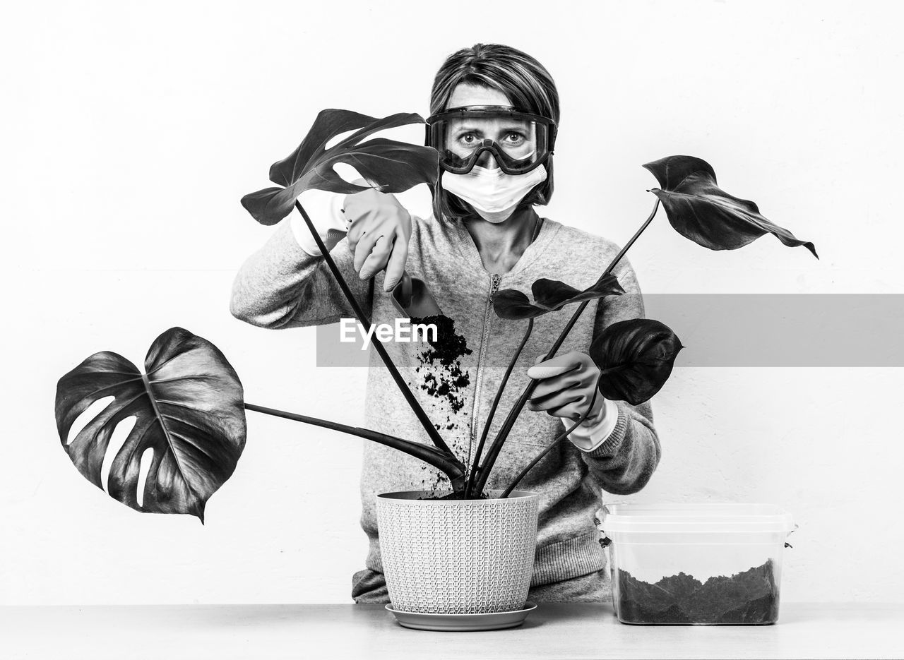 Portrait of woman with tropical plant monstera against white wall