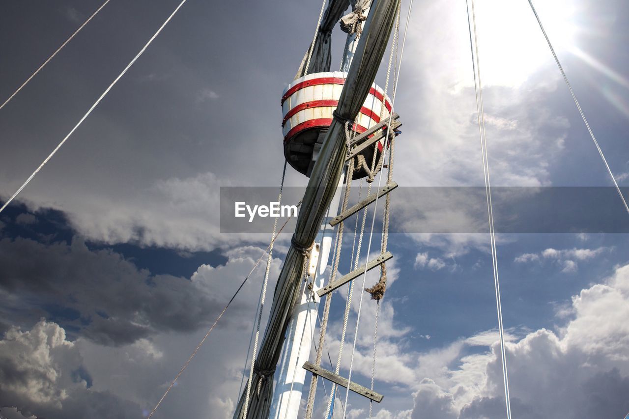 Low angle view of mast against cloudy sky