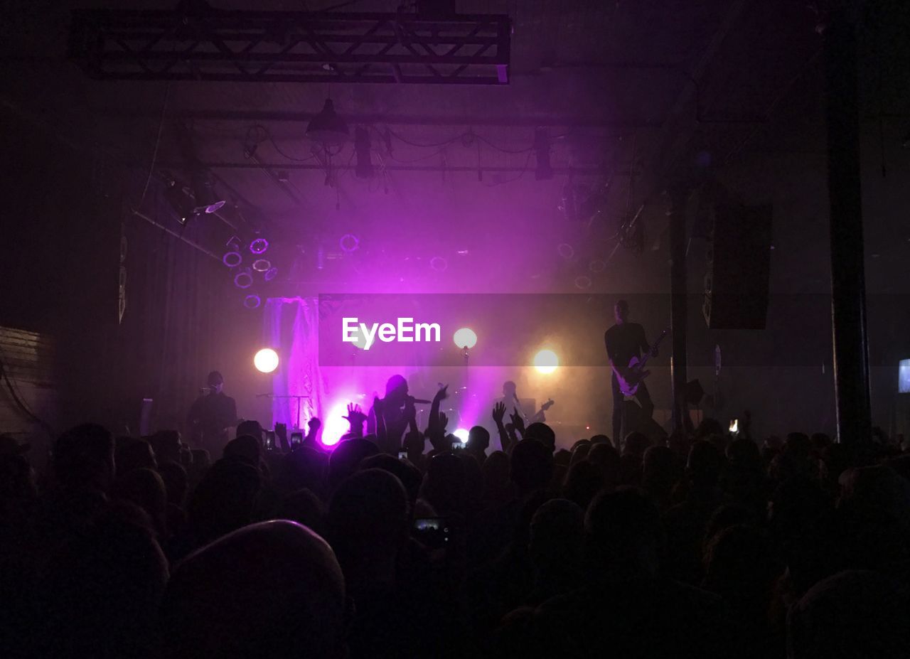 REAR VIEW OF PEOPLE ENJOYING MUSIC CONCERT AT NIGHT