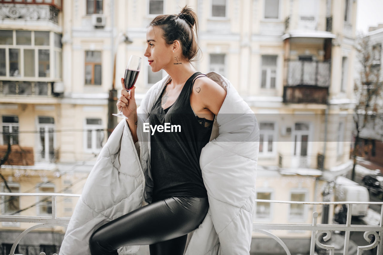 Side view of young woman standing in city