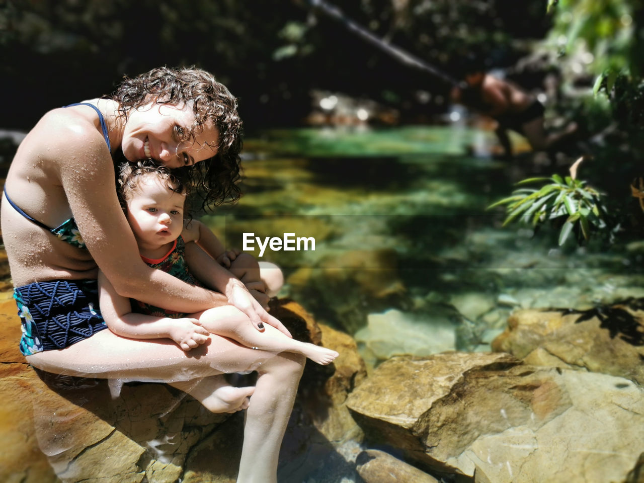 Mother and daughter cooling off in summer at waterfall.