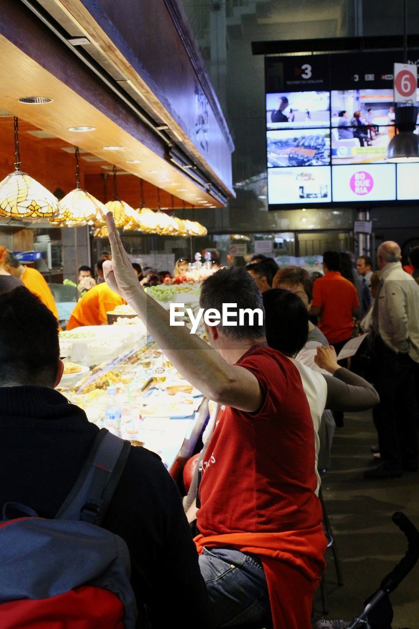 REAR VIEW OF PEOPLE SITTING IN SHOPPING MALL