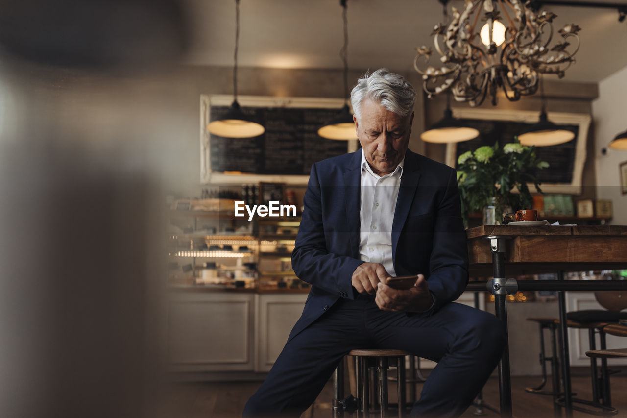 Senior businessman using cell phone in a cafe