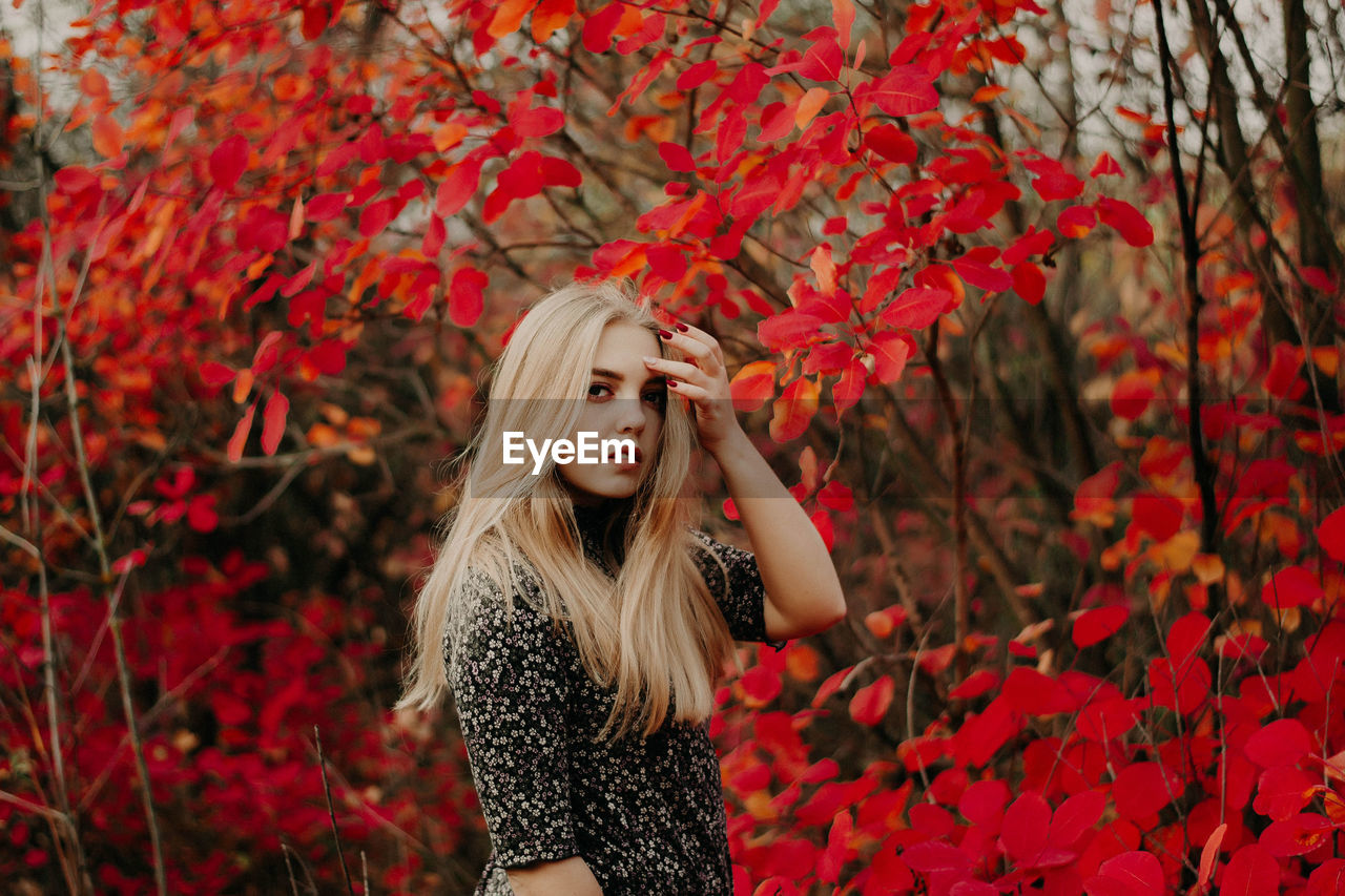 Full length of young woman standing on red autumn leaves