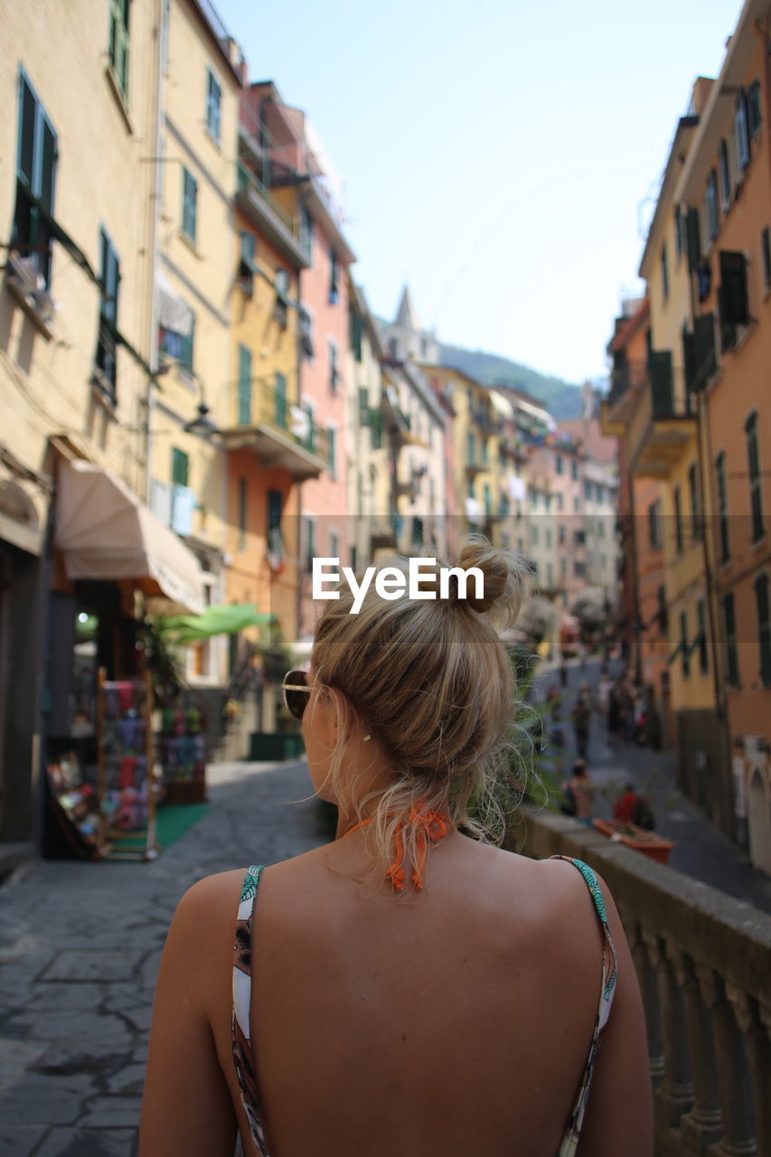 Woman in backless dress standing on street in city