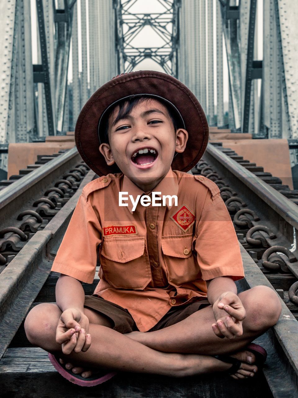 FULL LENGTH OF A SMILING BOY SITTING ON WALL