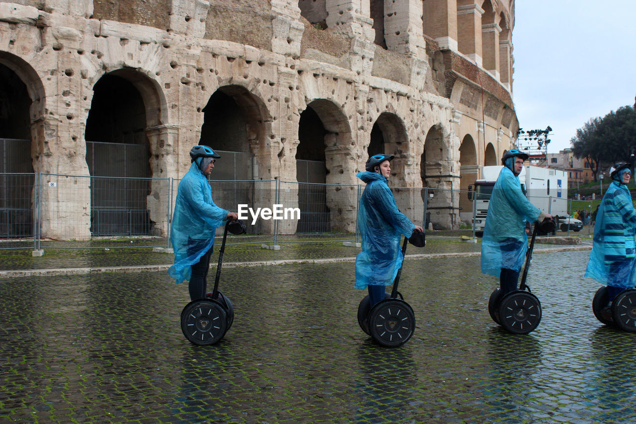 REAR VIEW OF PEOPLE WALKING ON TOWN SQUARE