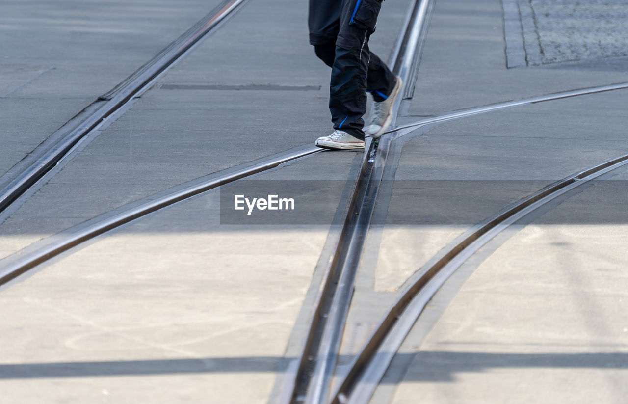 Low section of person walking on road with railroad track