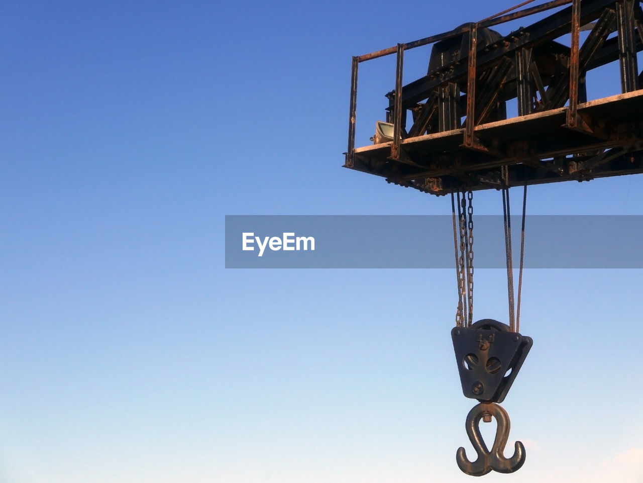 LOW ANGLE VIEW OF CRANES AGAINST CLEAR BLUE SKY