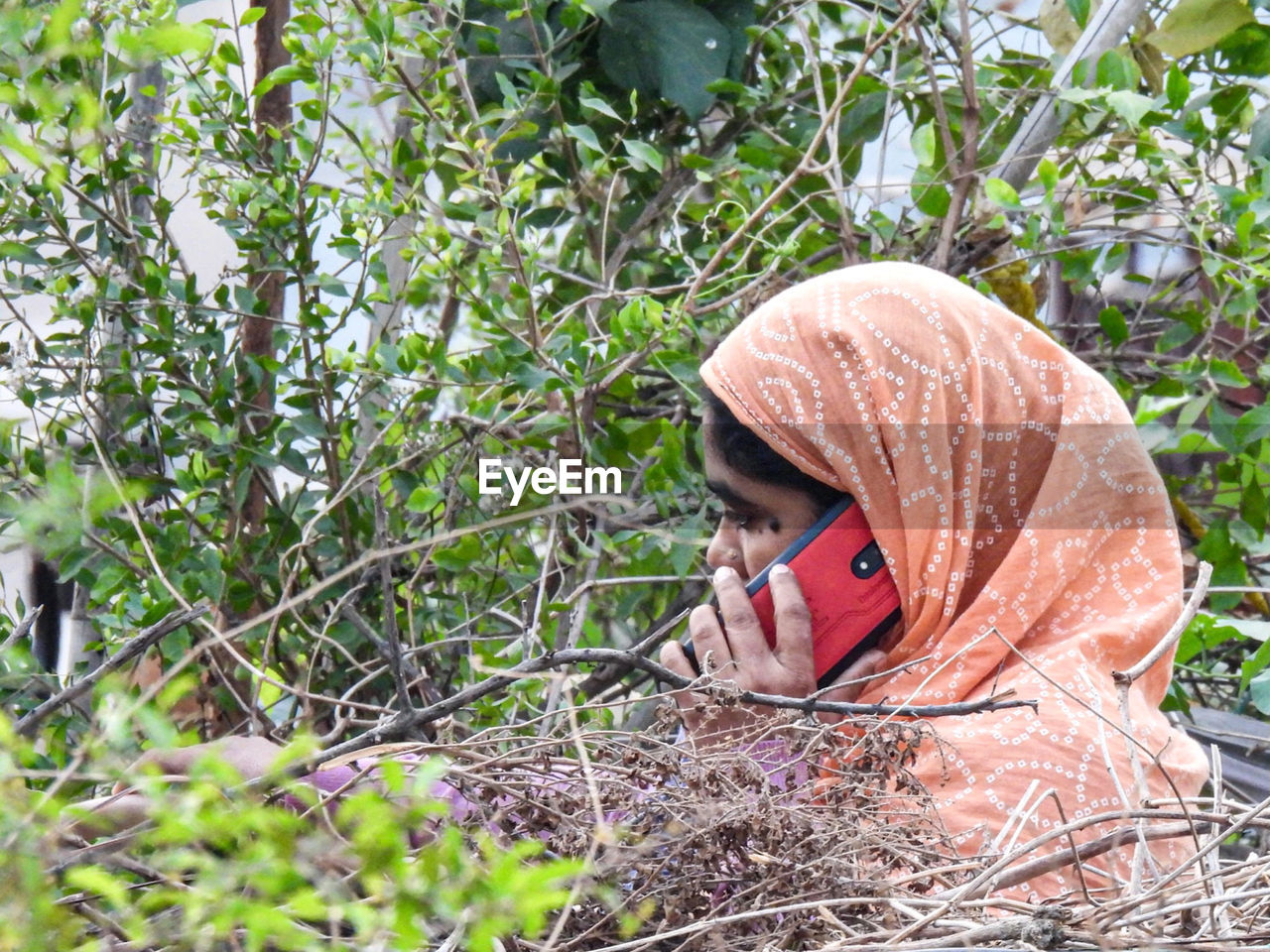 PORTRAIT OF WOMAN HIDING BEHIND PLANTS