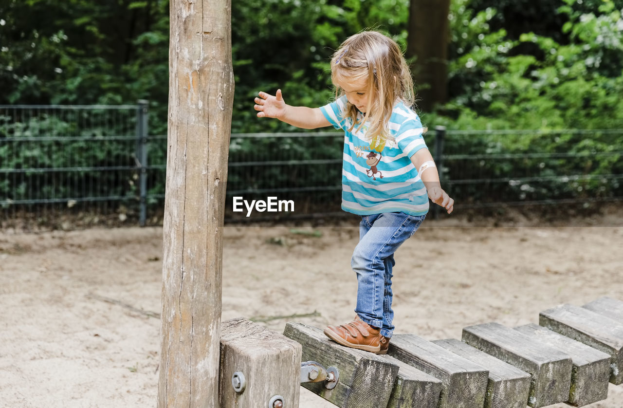 Full length of girl walking on wood in park