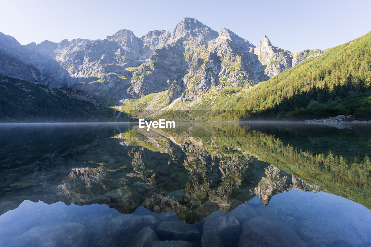 Majestic rocky mountain reflecting in pristine crystal clear alpine lake, poland, europe