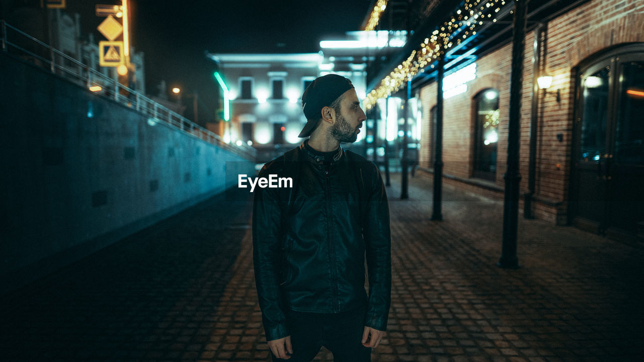 Man standing on footpath at night