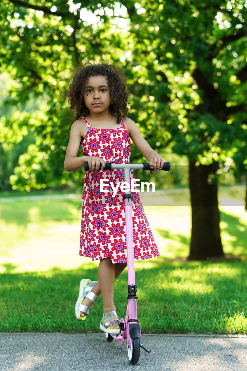 full length portrait of smiling young woman standing on field