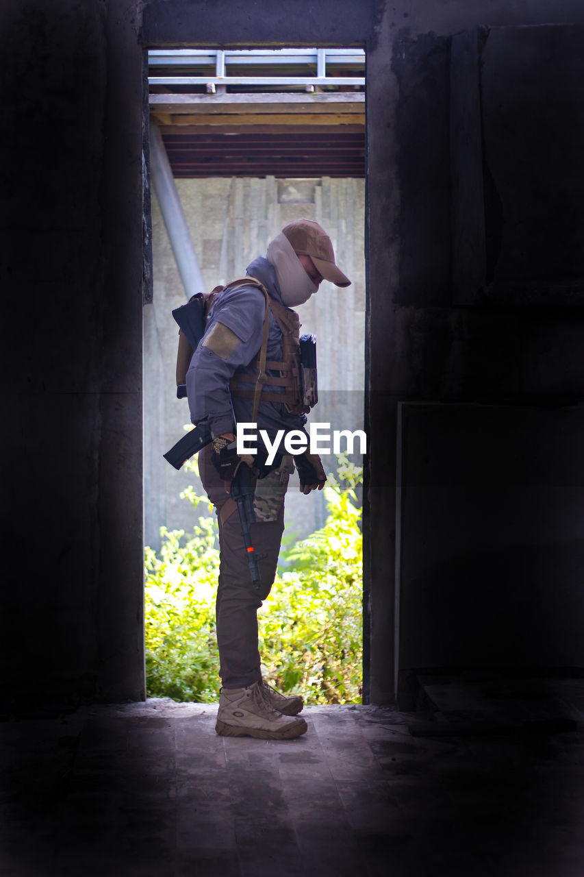 Side view of man standing against door