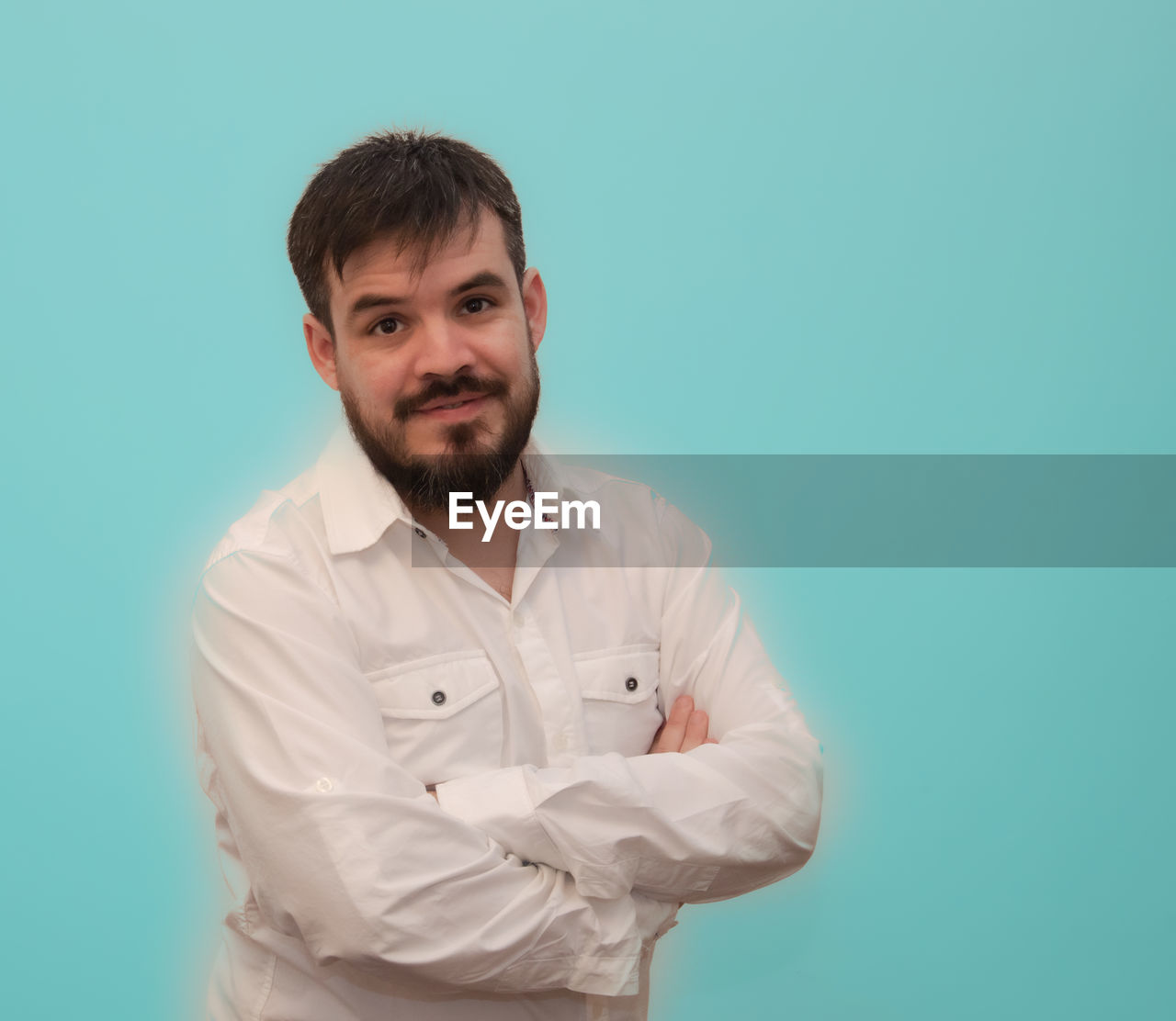 colored background, one person, studio shot, portrait, adult, looking at camera, indoors, men, beard, person, waist up, blue, facial hair, young adult, smiling, button down shirt, arms crossed, standing, occupation, blue background, front view, copy space, emotion, clothing, lab coat, happiness, human face, shirt, brown hair, white, casual clothing, green background