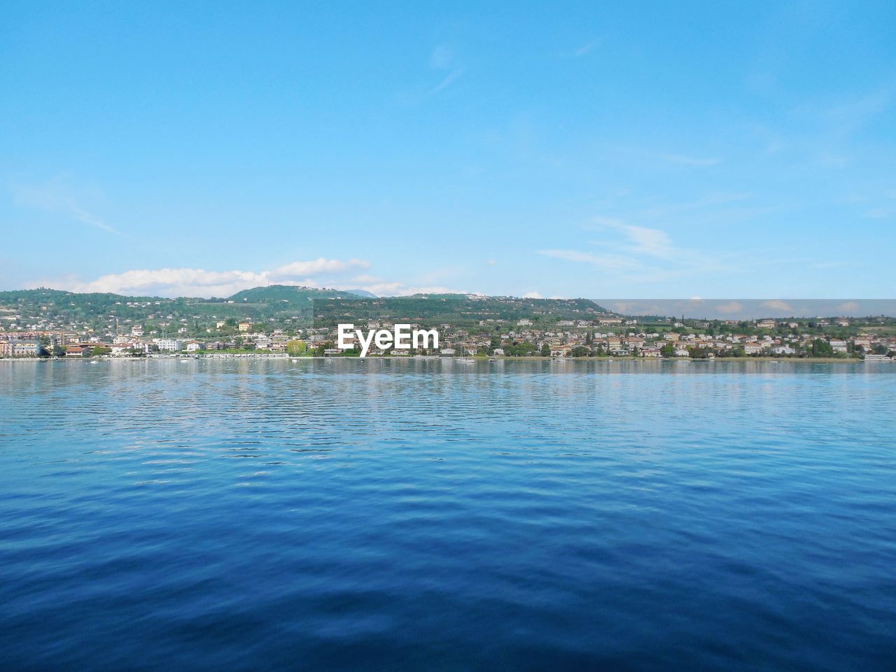 Scenic view of sea by town against blue sky